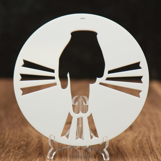 A white round acrylic ornament with a hand and rays coming out of the hand.
