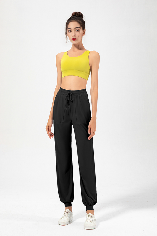 A female model wearing high-rise jogging pants and a yellow sports top.